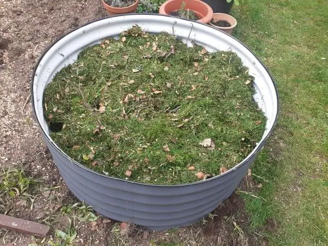 Metal raised bed by 'vegega' with infill material topped with grass clippings